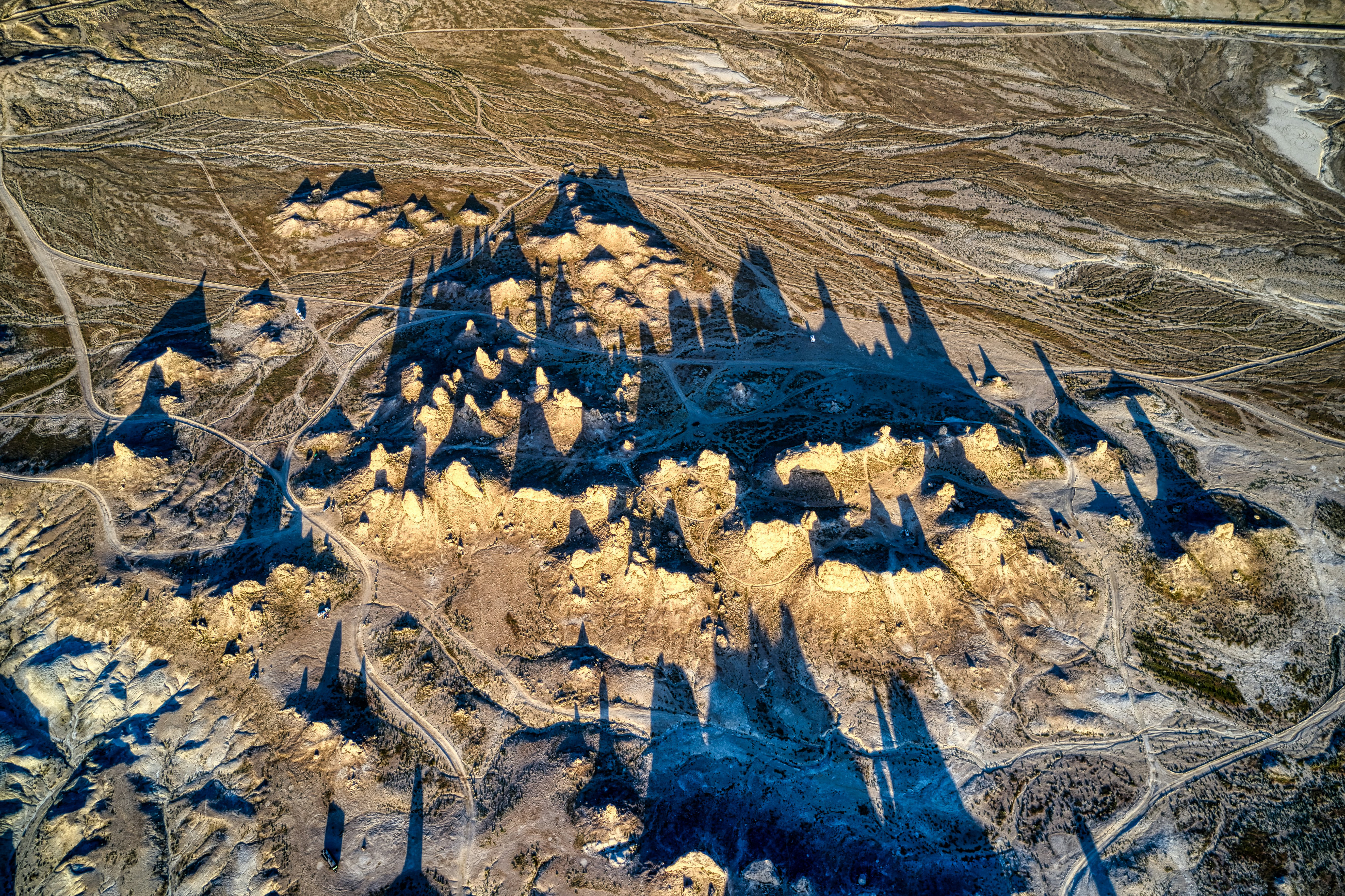 Epic historical Indian landscape — arid golden earth, dramatic overcast sky, dark rocky terrain, cinematic period drama atmosphere with deep shadows