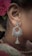 An intricately designed silver earring with black beads complements a traditional attire. A red floral hair accessory adds a touch of elegance, with fine detailing visible on both the earring and the fabric.