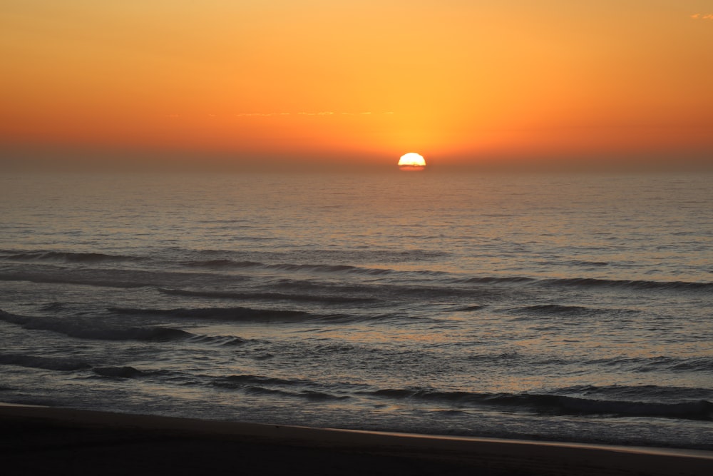 ocean waves crashing on shore during sunset