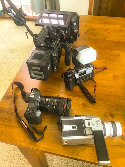 A vibrant display of various cameras set up on a wooden table, ready for filming.