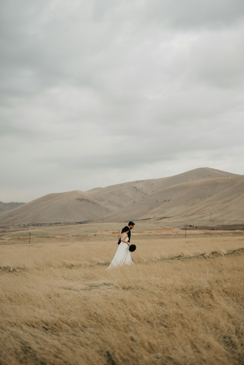 man and woman kissing on brown grass field during daytime