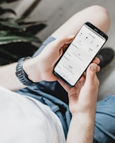 Close-up of hands holding a smartphone showing sales analytics charts.