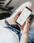 Hands holding a smartphone showing analytics and social engagement in a bright office.