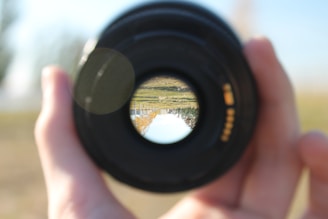 Close-up of a camera lens reflecting a scenic landscape.