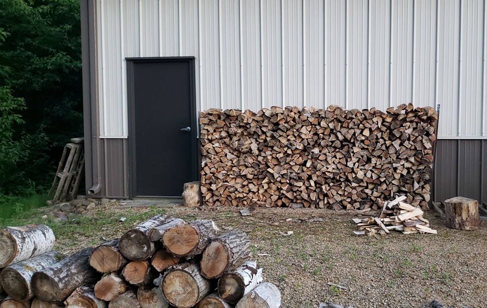 brown wood logs on green grass field near black wooden door