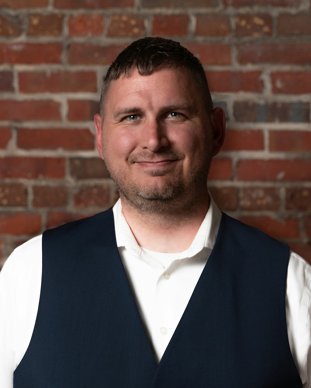 man in blue vest and white dress shirt