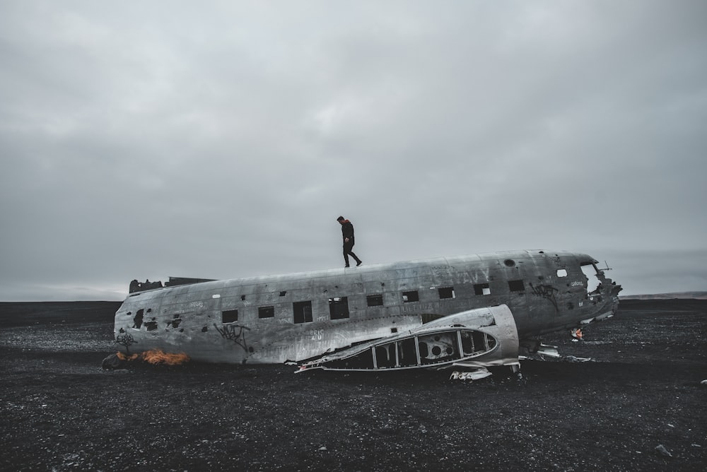 woman in red shirt standing on white airplane under white clouds during daytime