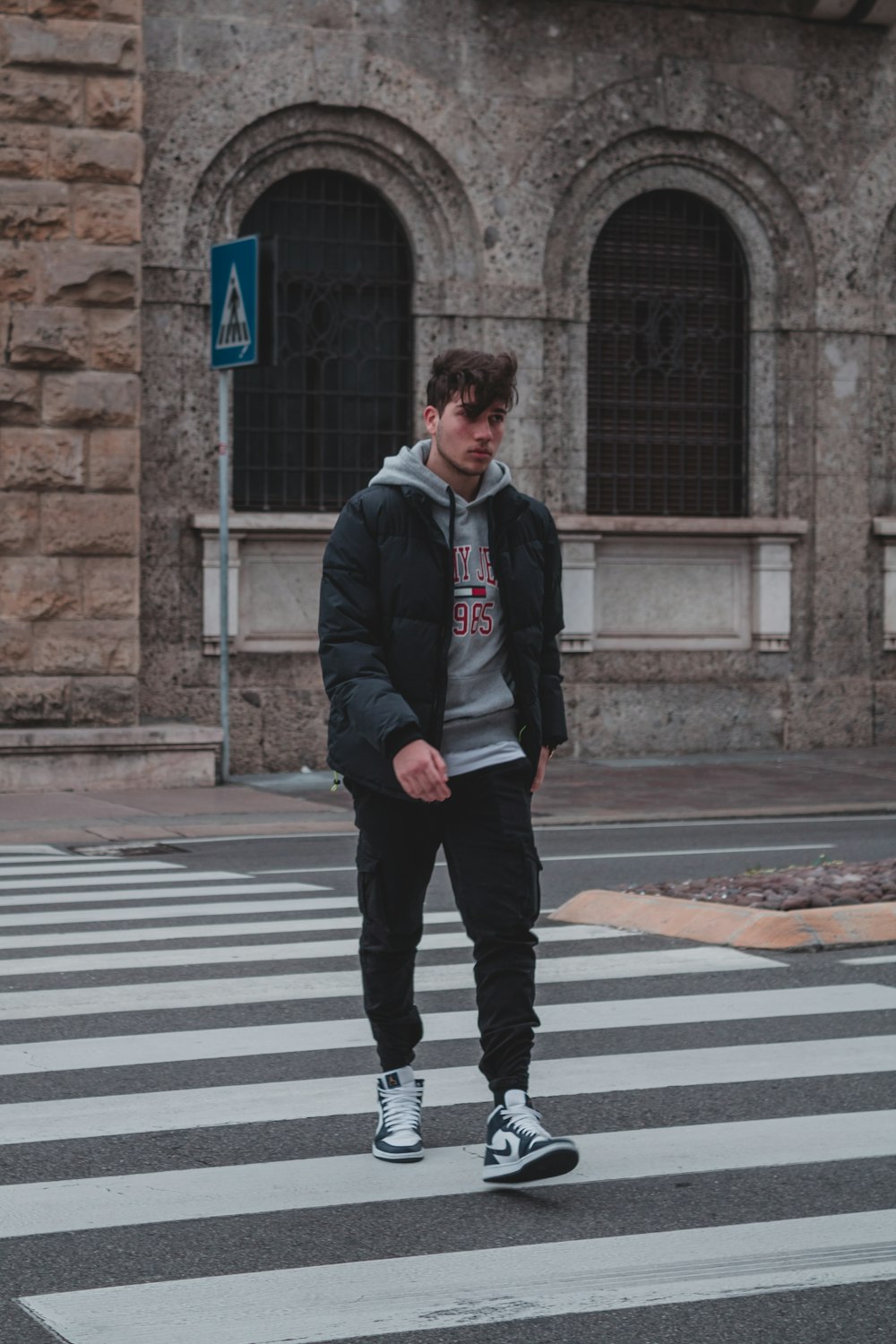 man in black jacket standing on pedestrian lane during daytime