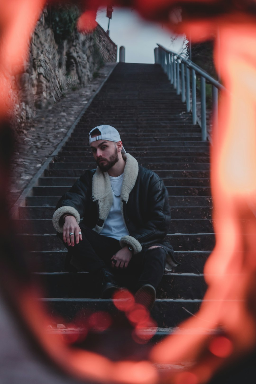 man in black jacket and black pants sitting on stairs