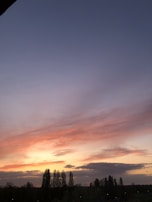 A serene scene of a sunset with silhouettes of anime characters drawn in the sky.