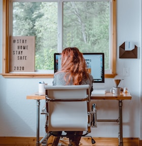 woman sitting on white and black chair in front of brown wooden table