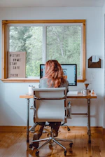Worker sitting at home, looking concerned while reviewing a dismissal letter.