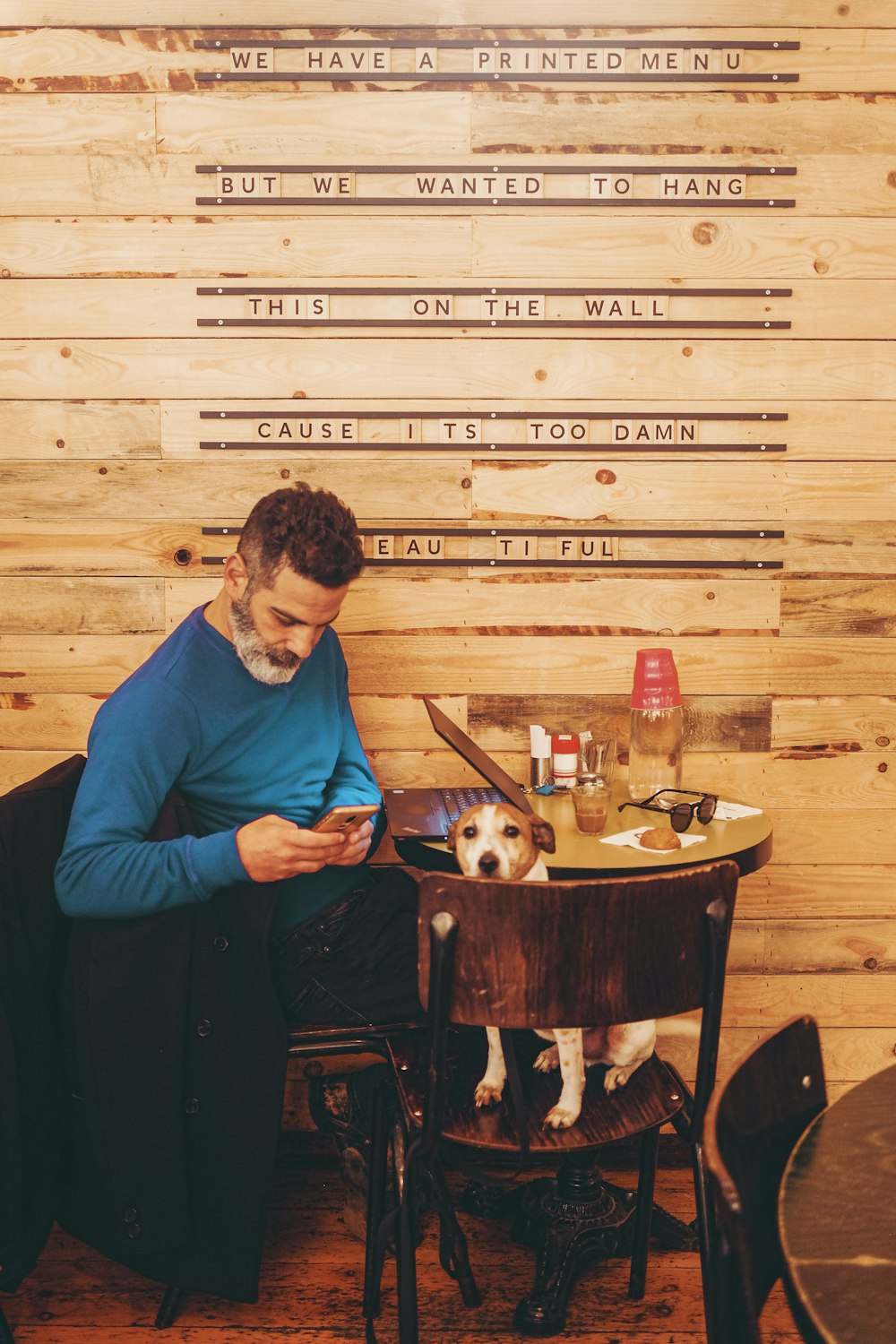 man in blue long sleeve shirt sitting on brown wooden seat