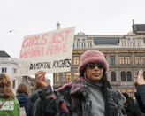 man in black jacket holding white and red signage