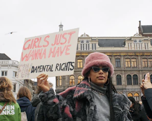 man in black jacket holding white and red signage