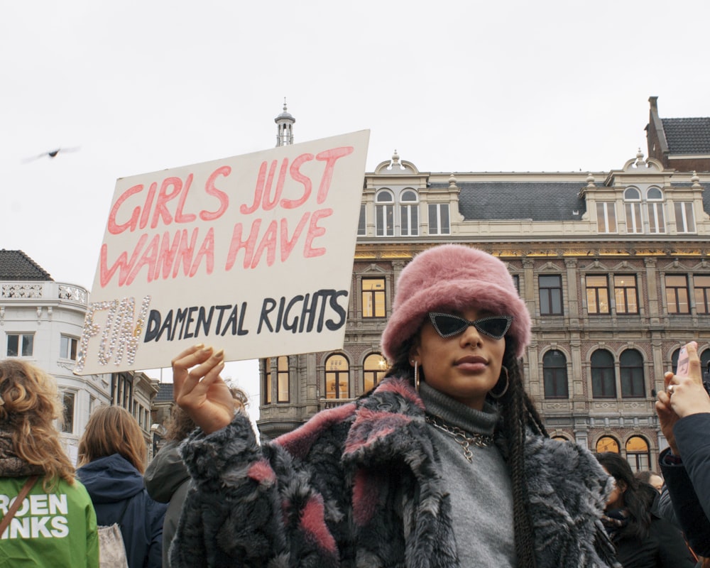 man in black jacket holding white and red signage