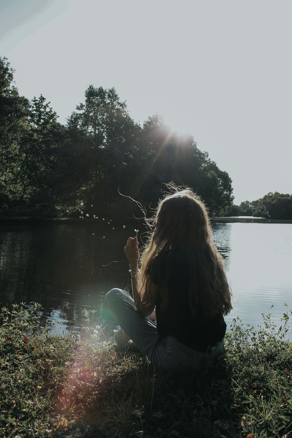 woman in black jacket sitting on green chair near lake during daytime