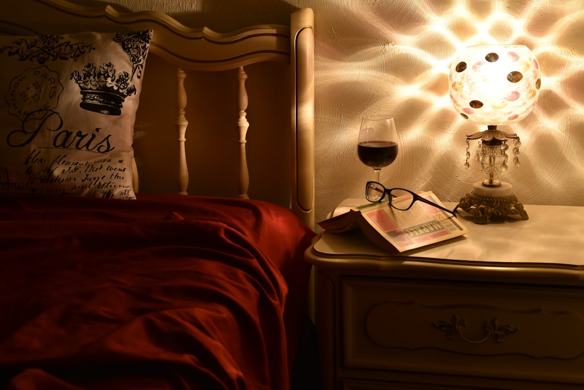 Eyeglasses resting on a nightstand beside a lamp, a calm bedtime routine