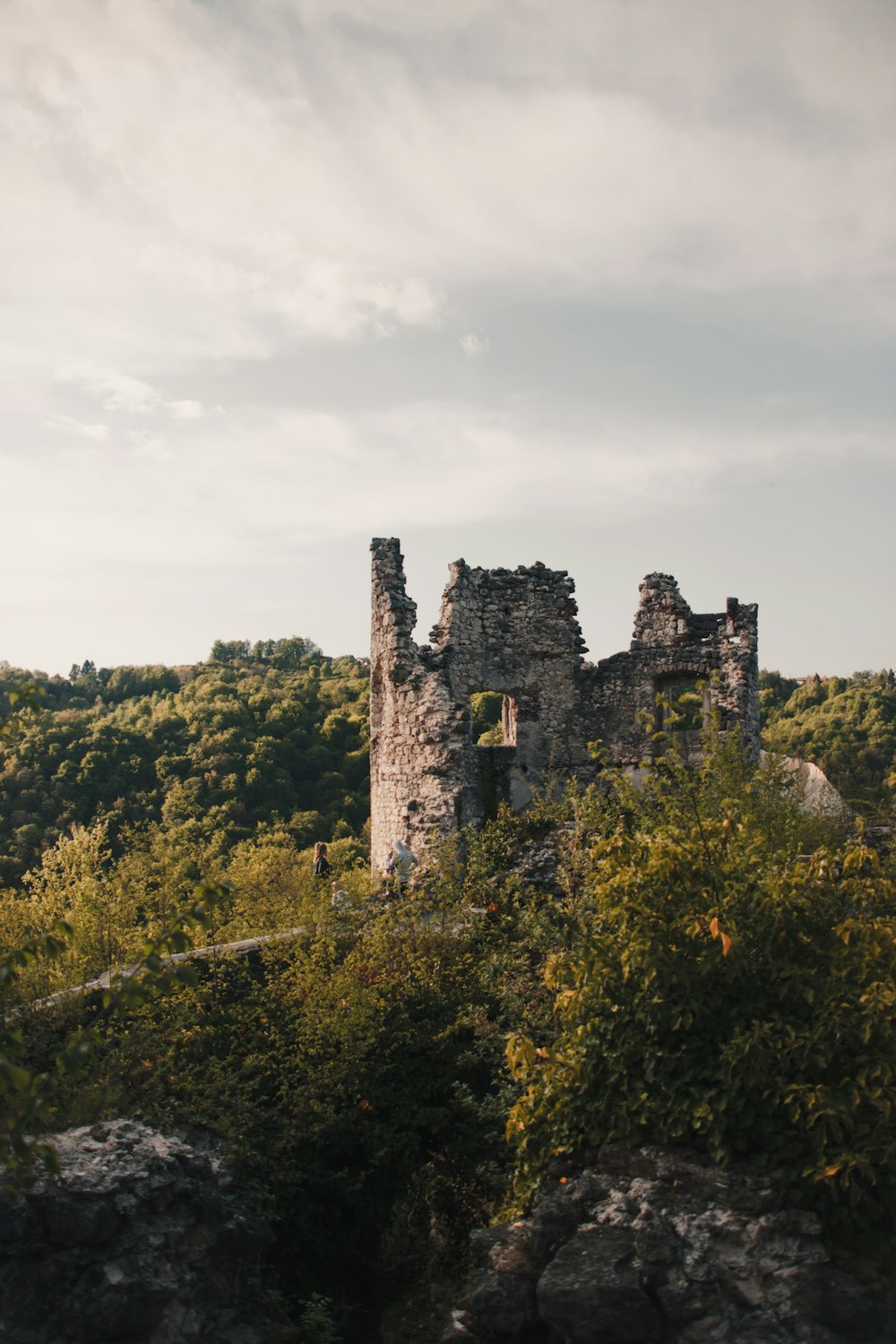 gray concrete castle on top of green mountain under cloudy sky during daytime