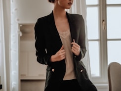 woman in black blazer standing near white wall