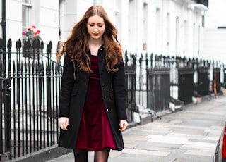 woman in black coat standing on sidewalk during daytime