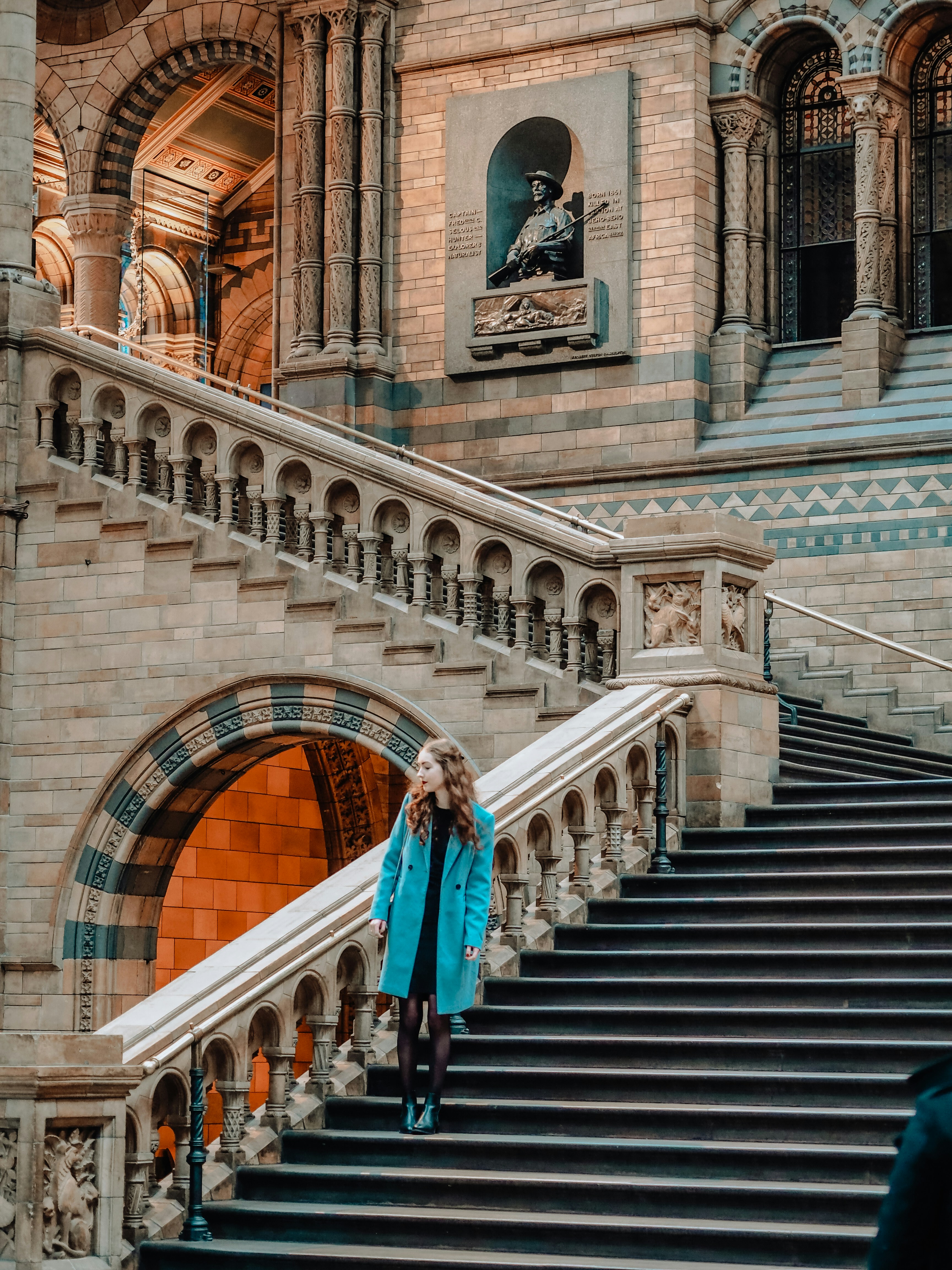 a woman in a blue coat walking down a set of stairs