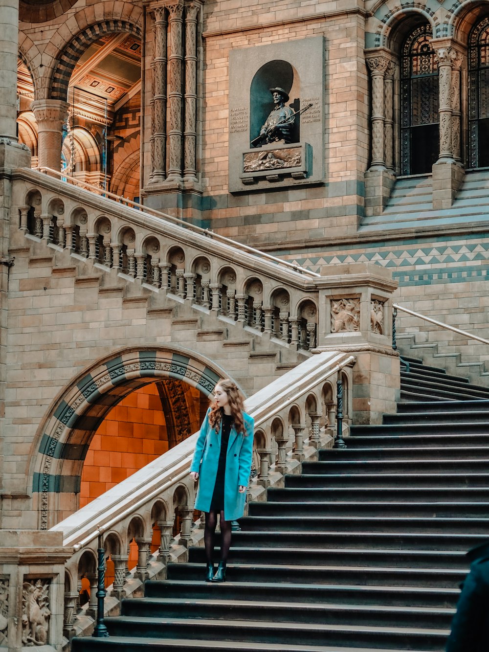 a woman in a blue coat walking down a set of stairs