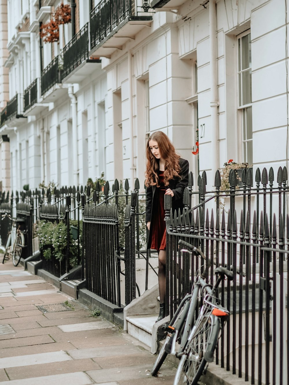 woman in black jacket standing beside black metal fence during daytime