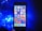 A smartphone with a colorful home screen is positioned upright against a dark backdrop. To the left, a cluster of bright blue LED lights casts an illuminating glow.