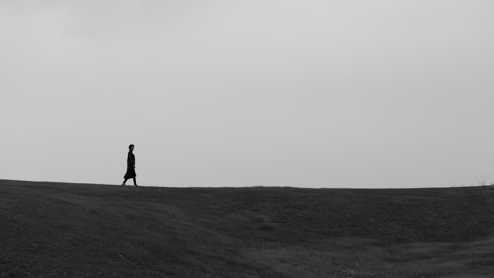 silhouette of person walking on field during daytime