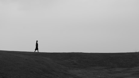 Silhouette solitaire marchant dans un paysage ouvert, illustrant l'ind&eacute;pendance &eacute;motionnelle