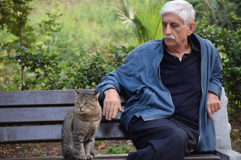 man in black jacket sitting on brown wooden bench