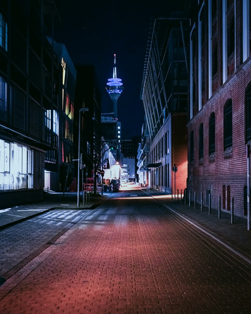 red brick road between buildings during night time