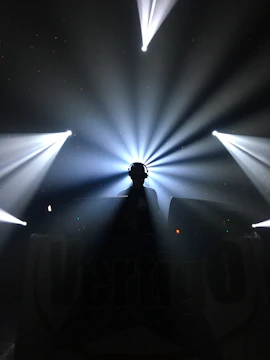 Artist silhouette holding headphones in front of a dimly lit studio