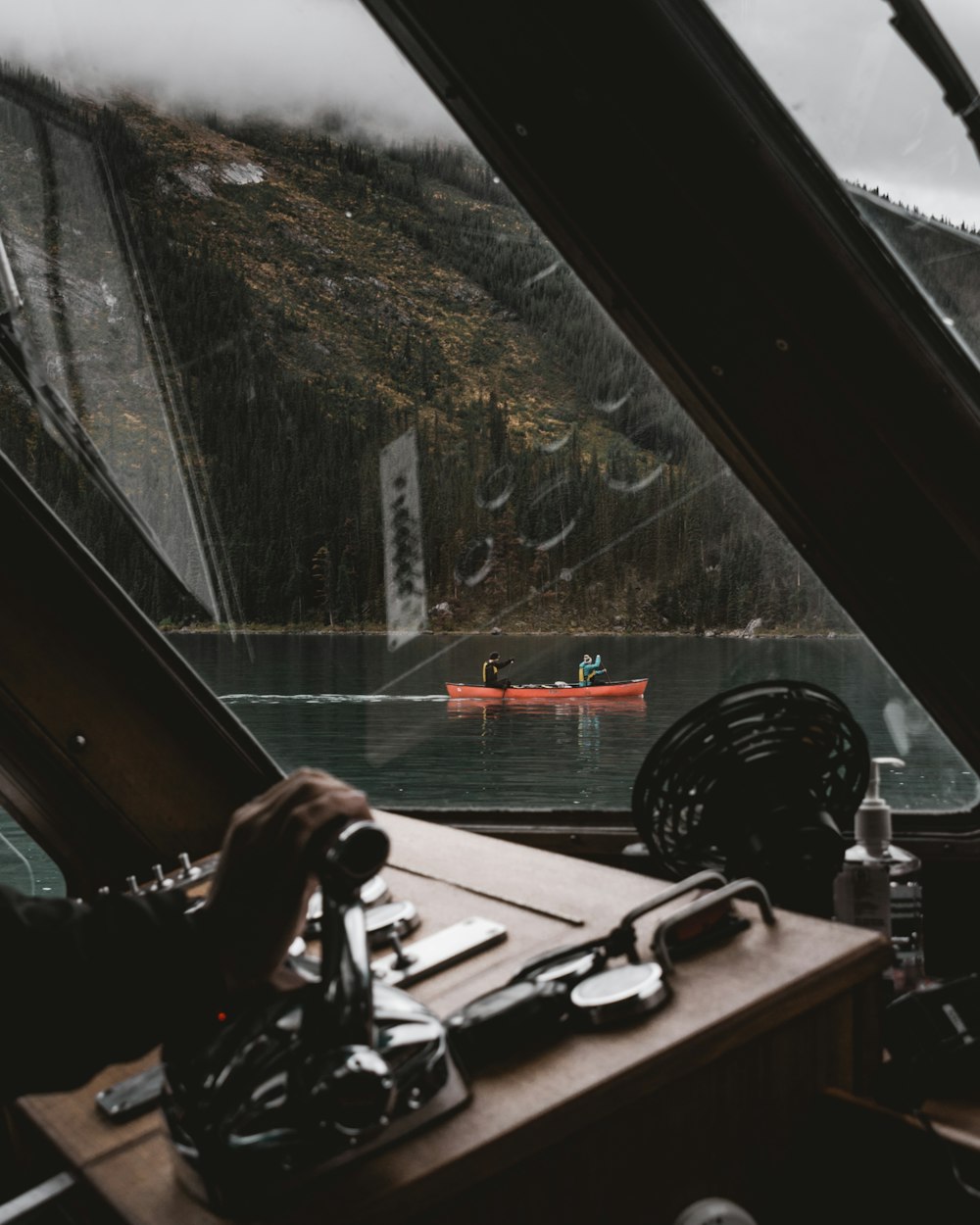 Personne tenant un appareil photo reflex numérique noir sur un bateau en bois brun pendant la journée