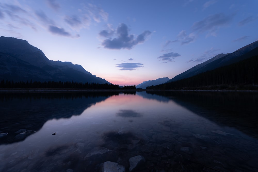 lake near mountain under blue sky during daytime