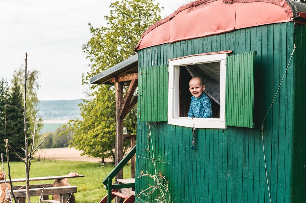 woman in blue jacket standing on red wooden shed during daytime