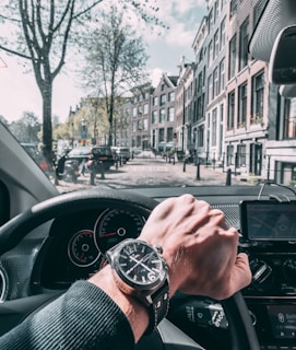 A smiling driving instructor guiding a student through a scenic Bern street.