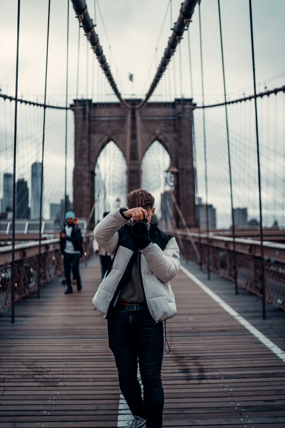 mulher na jaqueta branca que tira a foto da ponte do portão dourado durante o dia