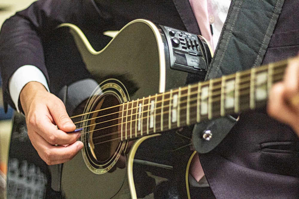 person holding black acoustic guitar