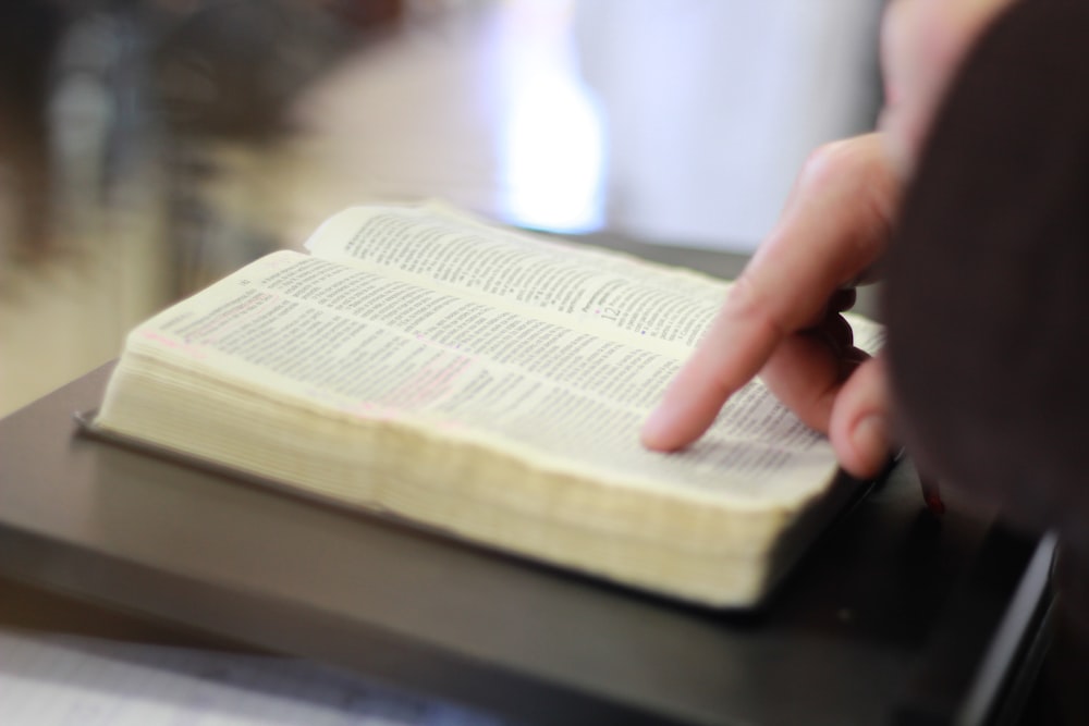 person holding book page on black table