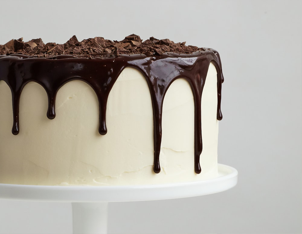 Tarta blanca con sirope de chocolate sobre plato de cerámica blanca