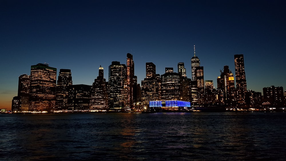 city skyline across body of water during night time