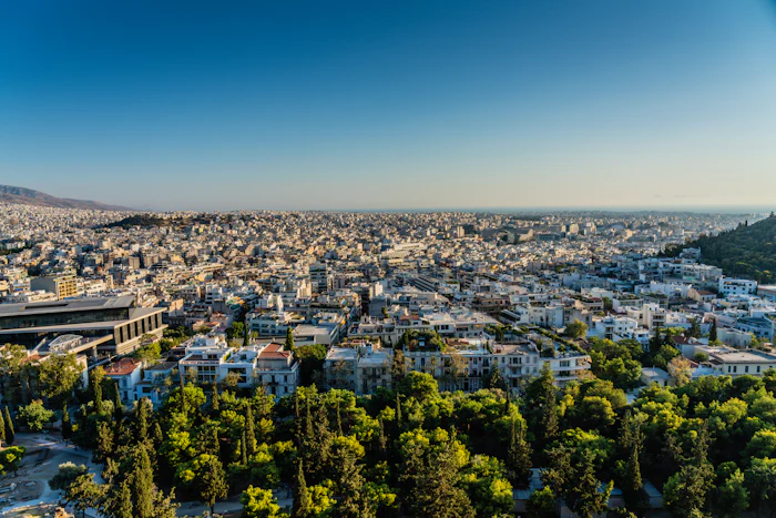 Athens rooftops from above, pine and the mountains behind.