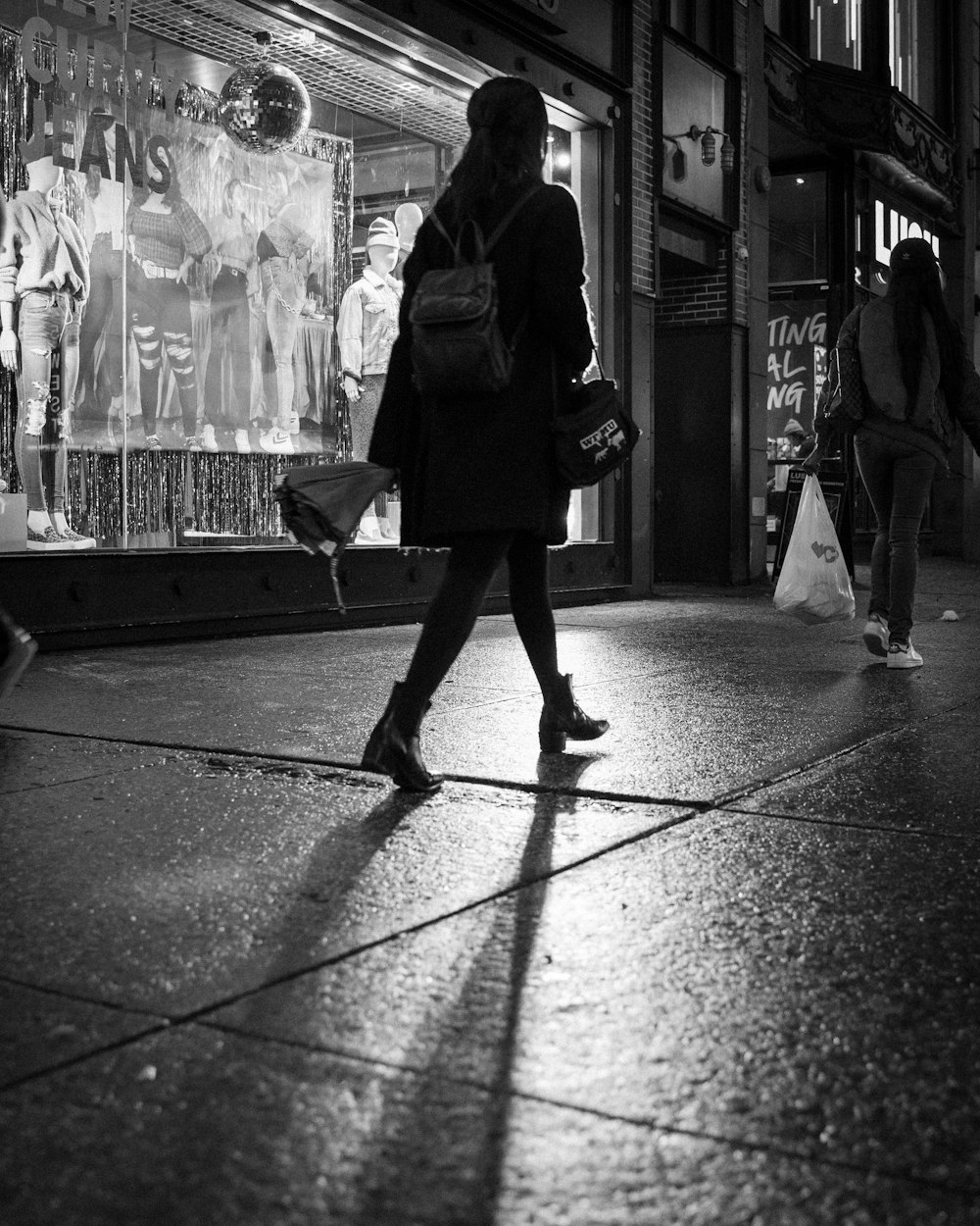 woman in black coat walking on sidewalk