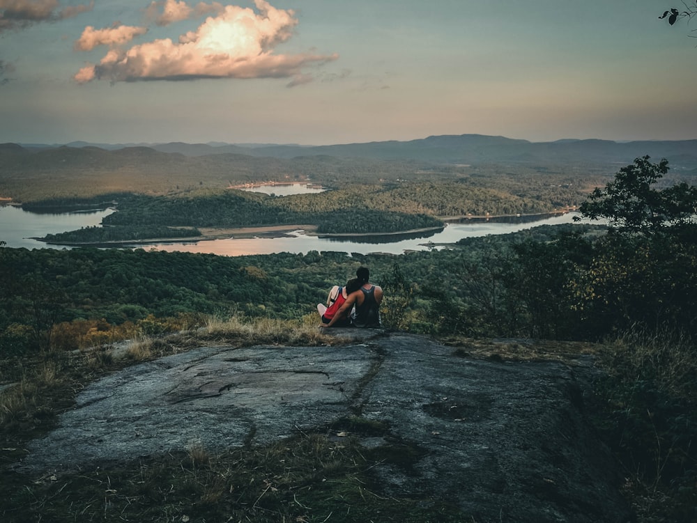 man and woman sitting on rock formation during daytime