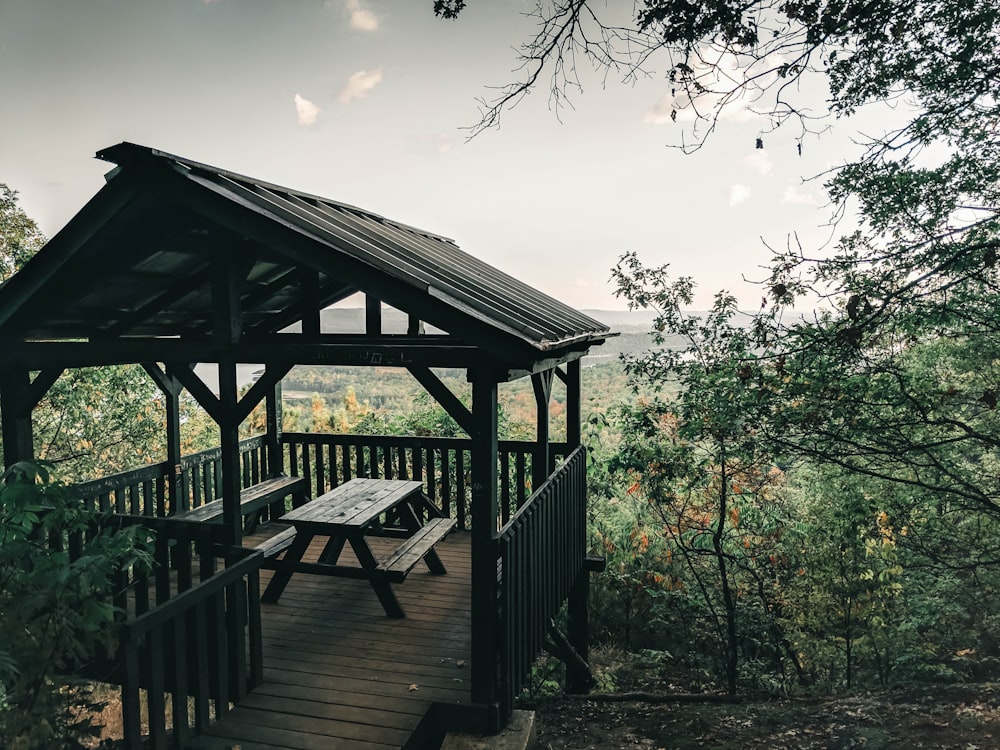 brown wooden gazebo surrounded by green trees during daytime