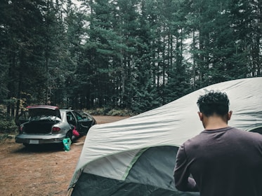 Close-up of the inflatable airframe being quickly set up by a camper in a forest.