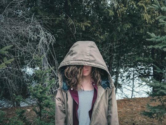 woman in brown coat standing near green trees during daytime in Wakefield Canada