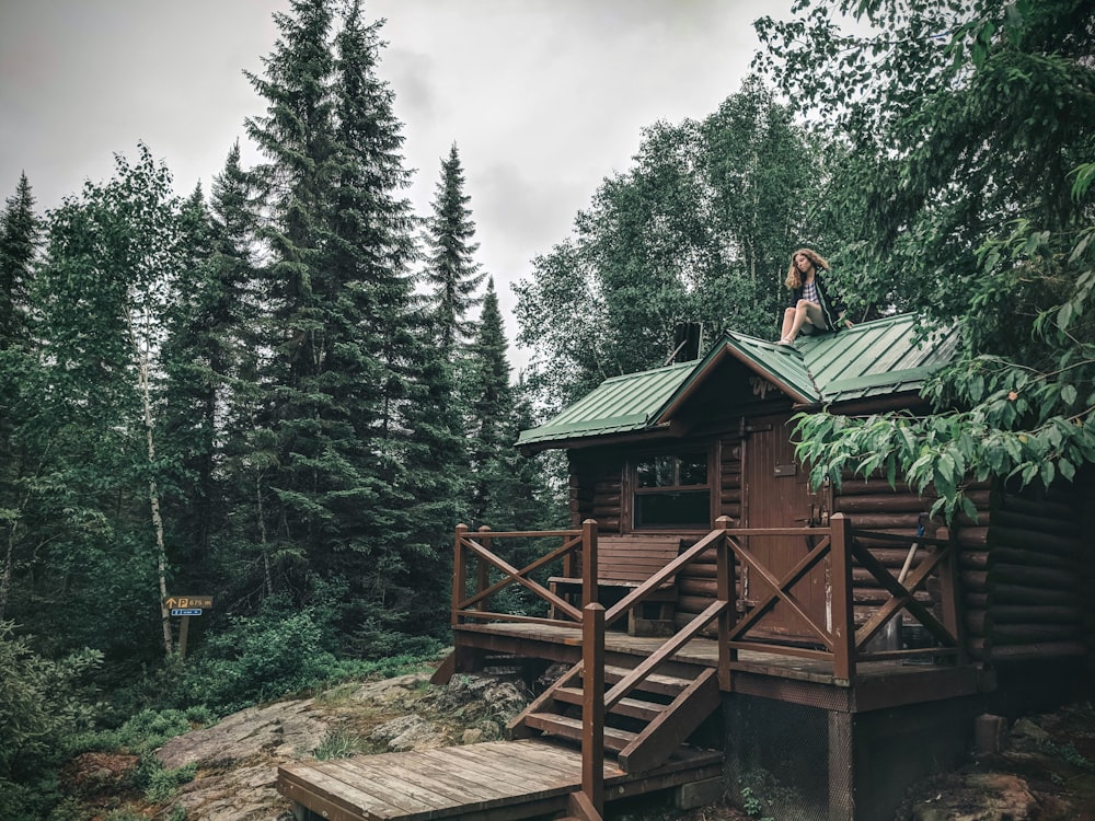 woman in black jacket standing on brown wooden dock near green trees during daytime